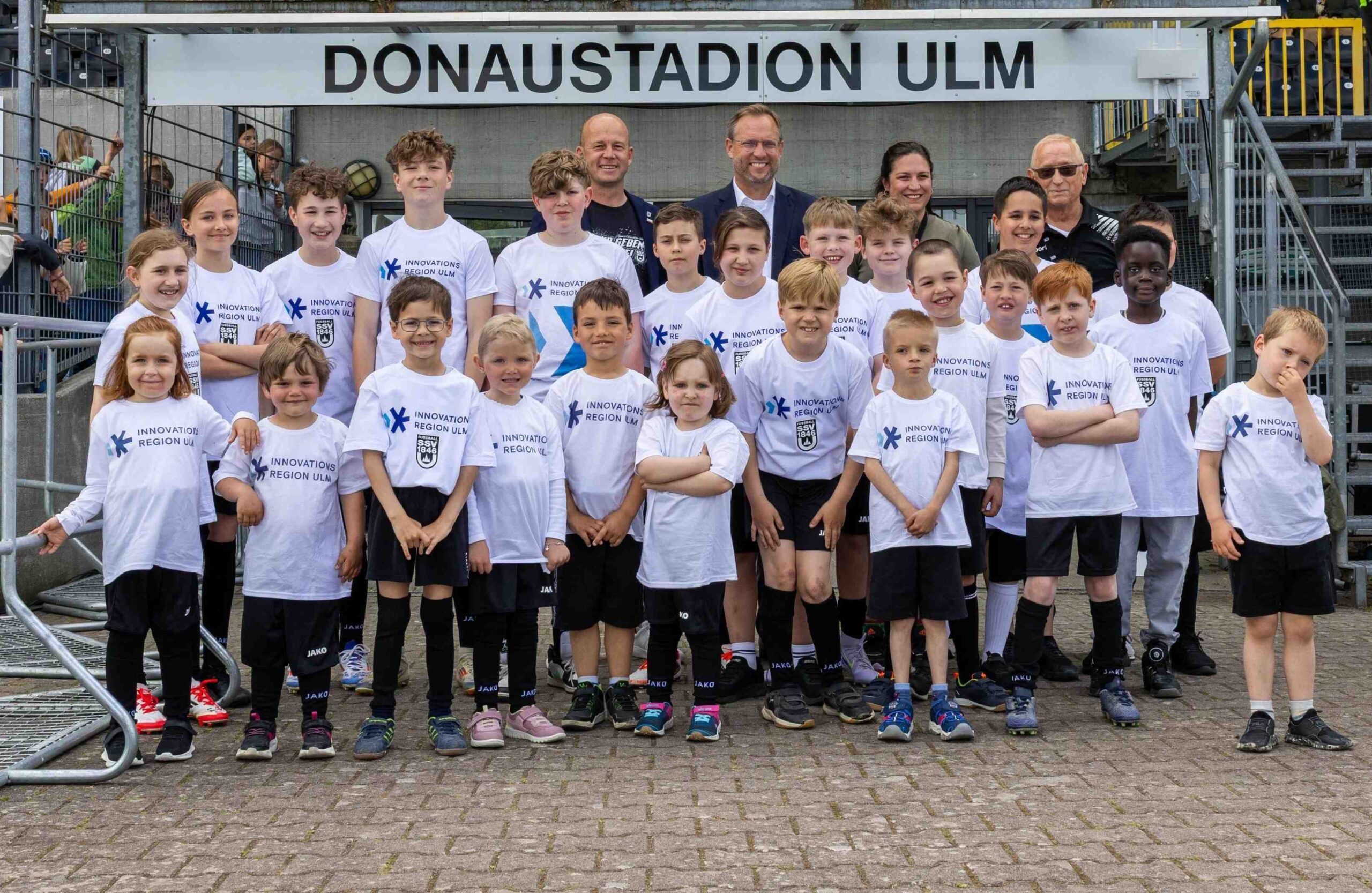Einlaufkinder der Uniklinik Ulm im Donaustadion mit Markus Thiele, Geschäftsführer des SSV Ulm 1846 Fußball, Martin Ansbacher, Oberbürgermeister der Stadt Ulm und Vorstandsmitglied der Innovationsregion Ulm, Simone Strobel, Geschäftsführerin der Innovationsregion Ulm und Werner Kühne, SSV Ulm 1846 Fußball
