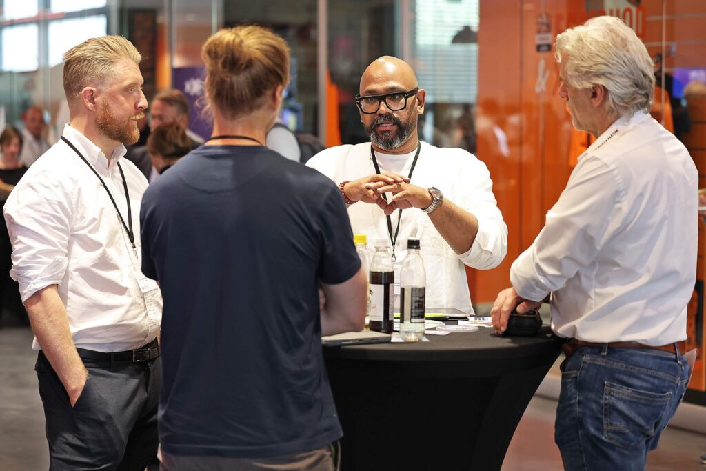 Vier Maenner diskutieren bei einem Networking-Event an einem Stehtisch.