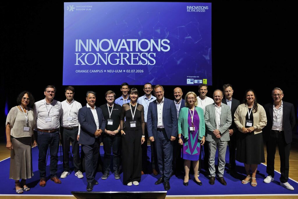Eine Gruppe von Personen posiert vor einem Innovationskongress-Banner.