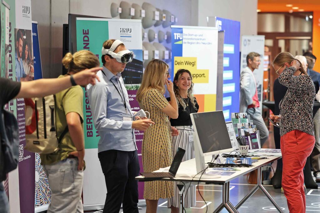 Besucher auf einer Messe nutzen VR-Brillen und interagieren mit Technik.