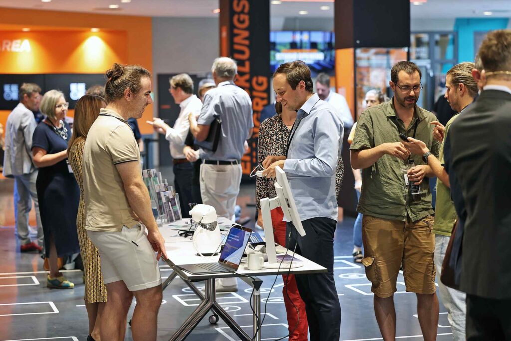 Menschen stehen und unterhalten sich an einem Stand auf einer Messeveranstaltung.