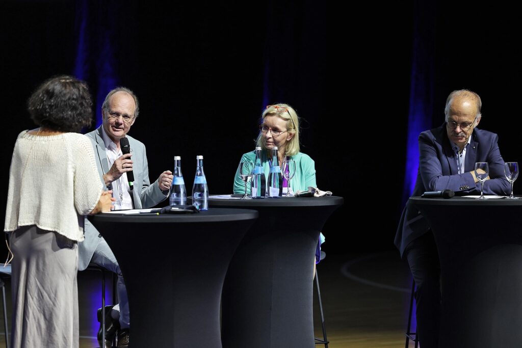 Eine Gruppe von Personen sitzt an einem Podiumstisch waehrend einer Diskussion.